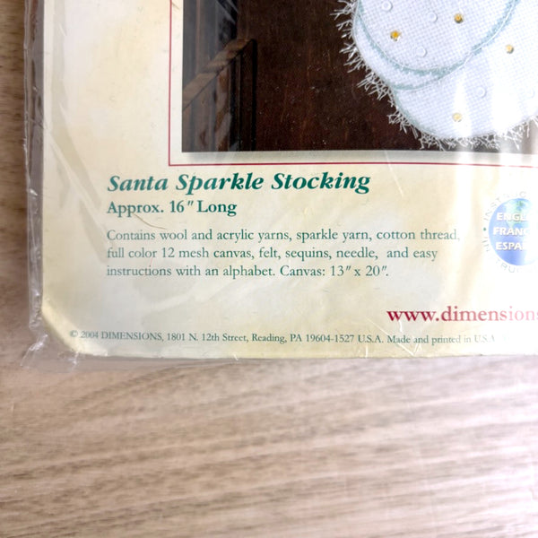 Dimensions Santa Sparkle Stocking kit packaging on a wooden surface
